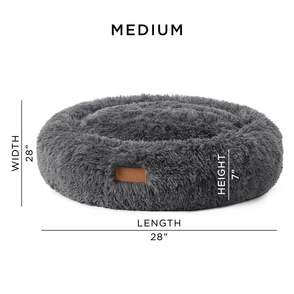 Town & Country Luxe CuddleTown cama donut gris oscura en sala cálida.